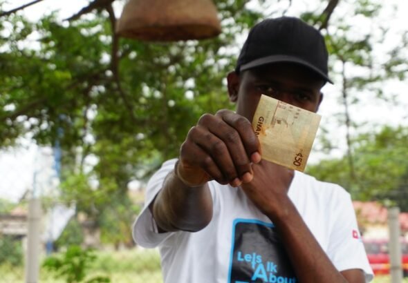 Real editorial stock photograph illustrating cash and digital payment use; not a photograph of the Bank of Ghana pilot